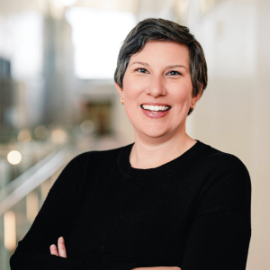 Jen Fenton standing in a well-lit building with arms crossed for a headshot
